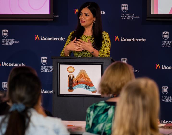 Maryam Popal Zahid speaking in front of sitting women attendees